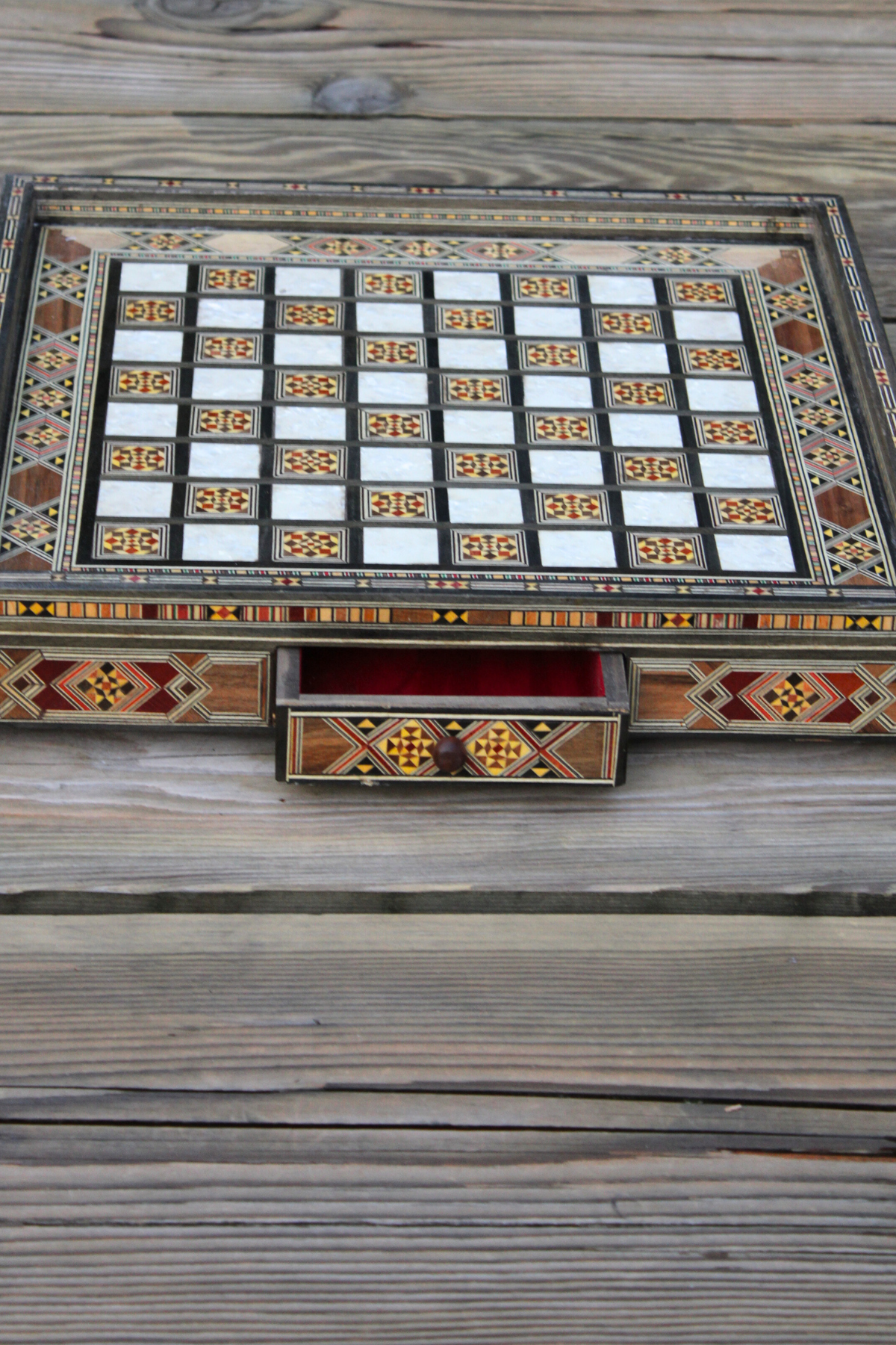 Open drawer of the handcrafted chess board, revealing the spacious storage area while showcasing the elegant wood finish and the board’s intricate craftsmanship, with no chess pieces present.