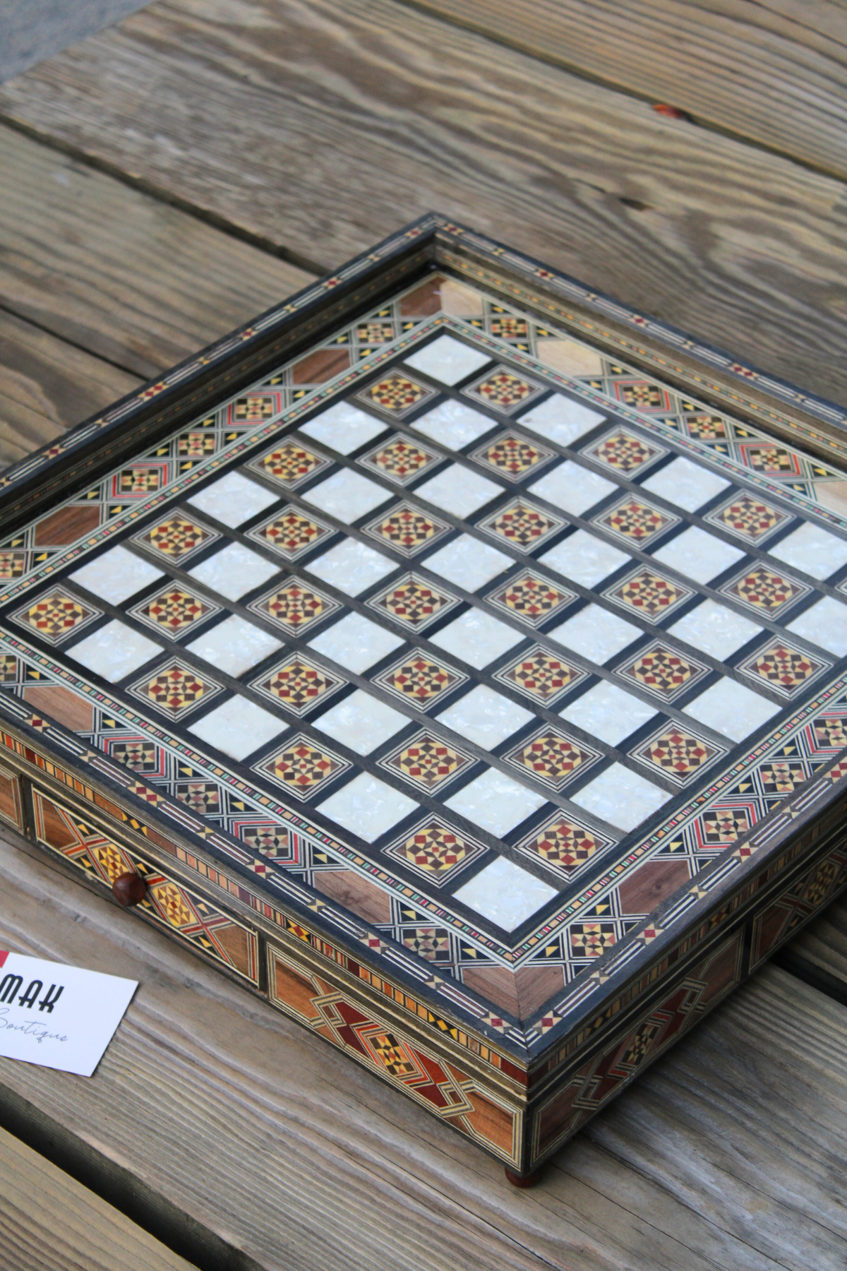 Side view of the handcrafted chess board with the drawer closed, showcasing the intricate pattern and elegant wood finish, emphasizing the exquisite craftsmanship and beauty of the set.
