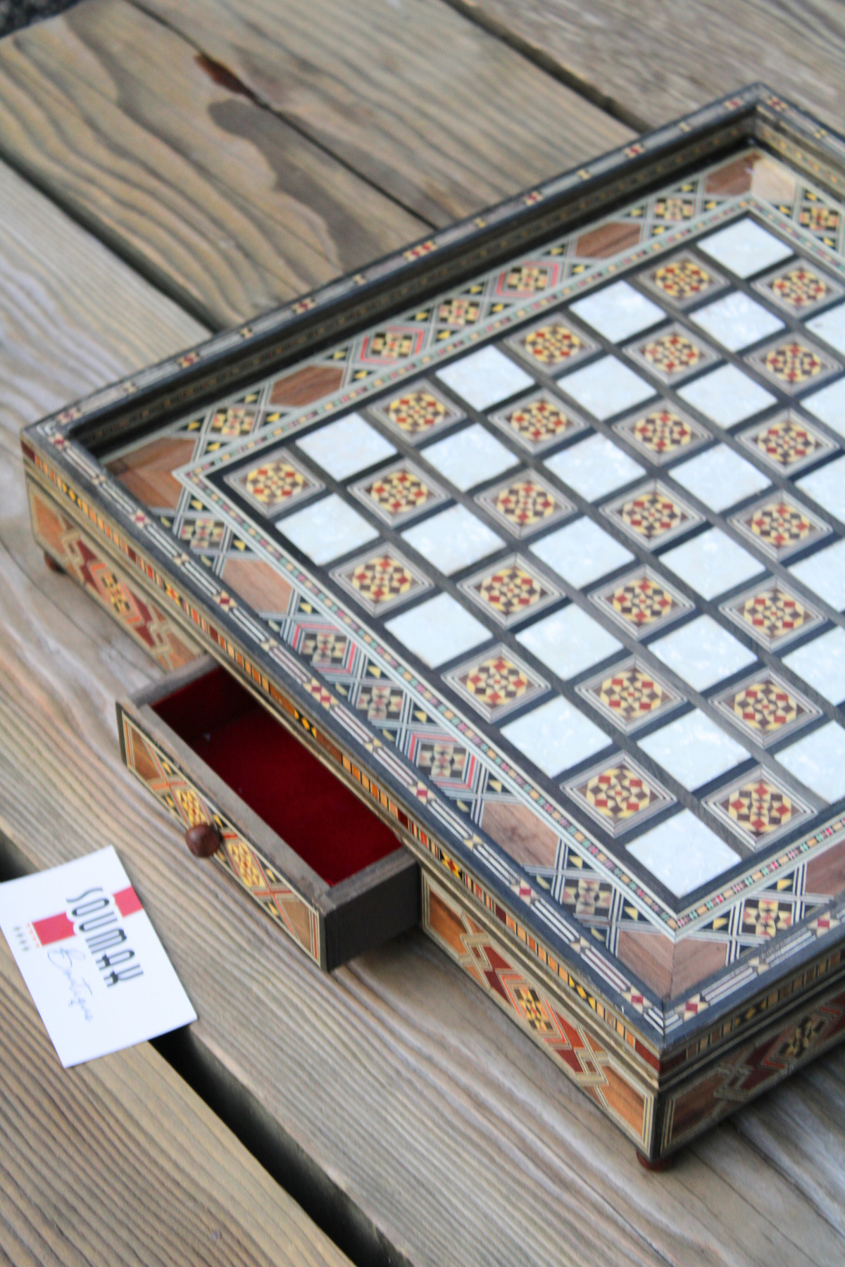 Side view of the handcrafted chess board with one drawer open, showcasing the elegant design and craftsmanship, while revealing the spacious storage area alongside the rich wood texture of the board.