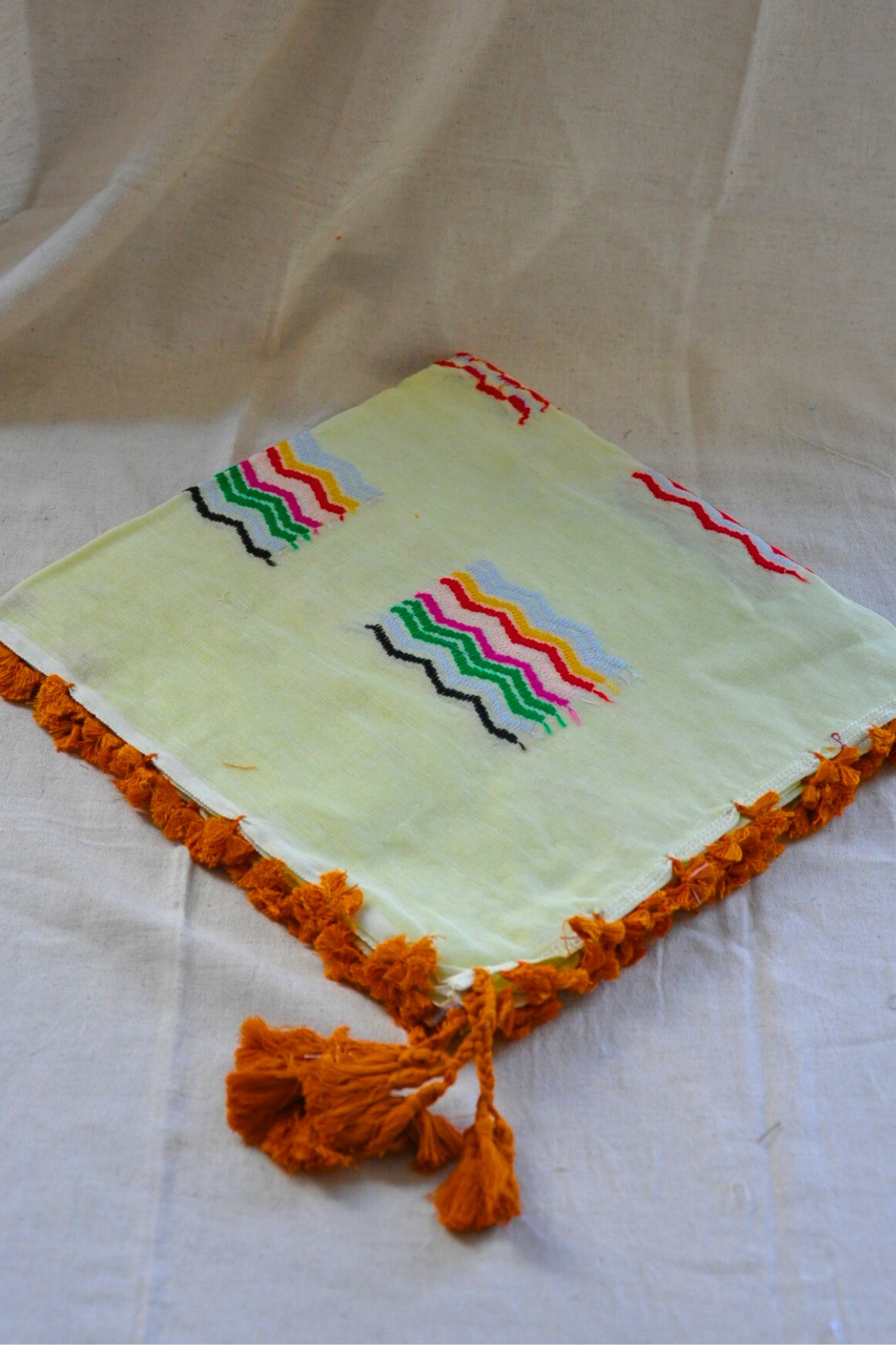 A vibrant display of the Lemon Kuffiyeh scarf on a stylish table, highlighting its cheerful color and artistic patterns that attract attention.