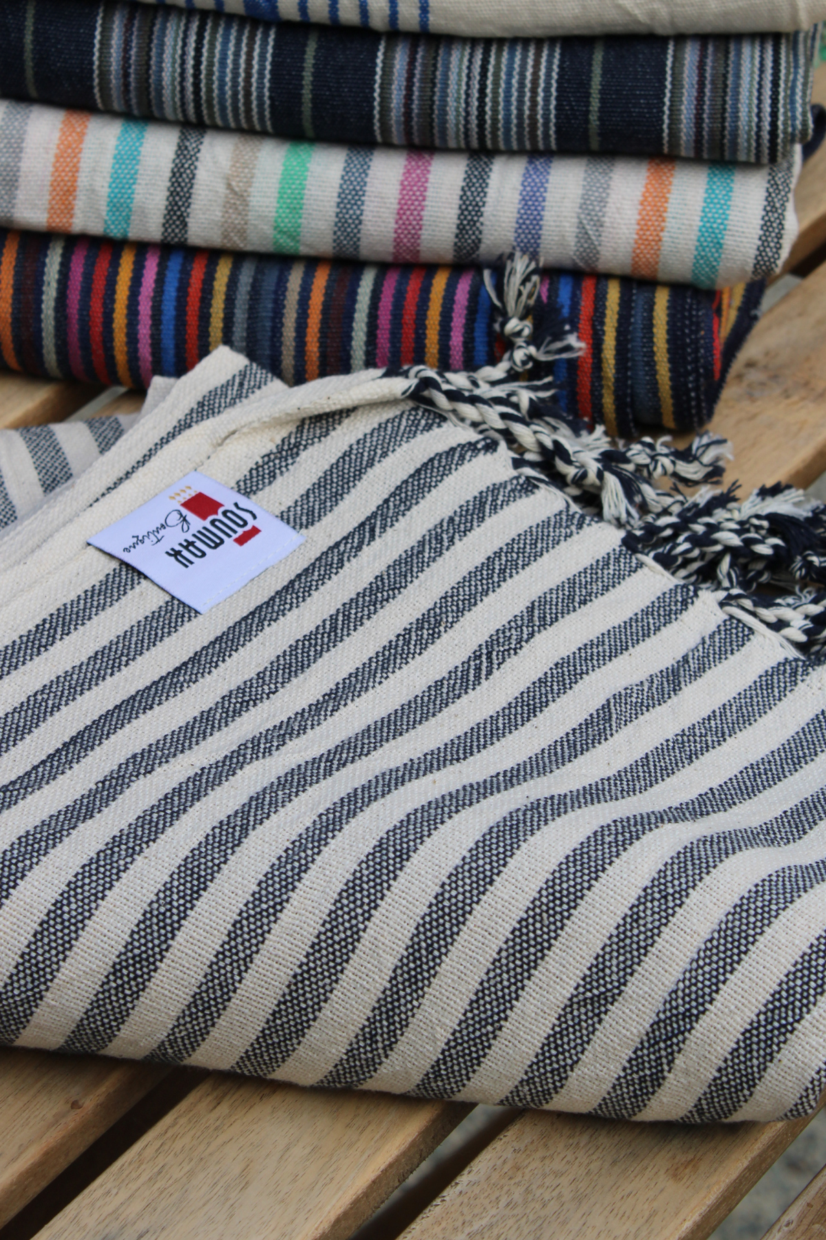 The Turkish Hamam Towel is rolled and displayed, showcasing the soft texture and striking charcoal stripes.
