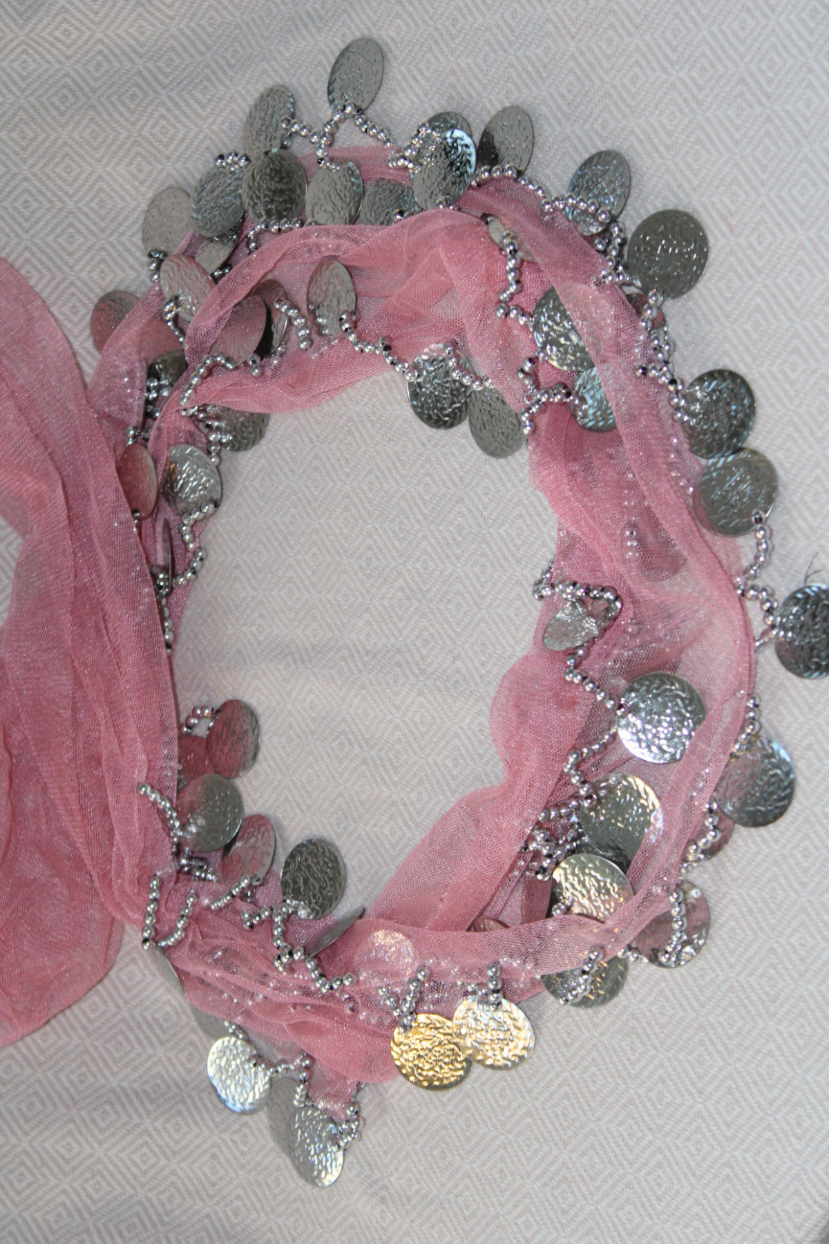 A soft pink belly dance waist chain with two layers of silver coins. The pastel pink color adds a feminine, playful touch, while the shimmering silver coins bring elegance and movement to your belly dancing performance.