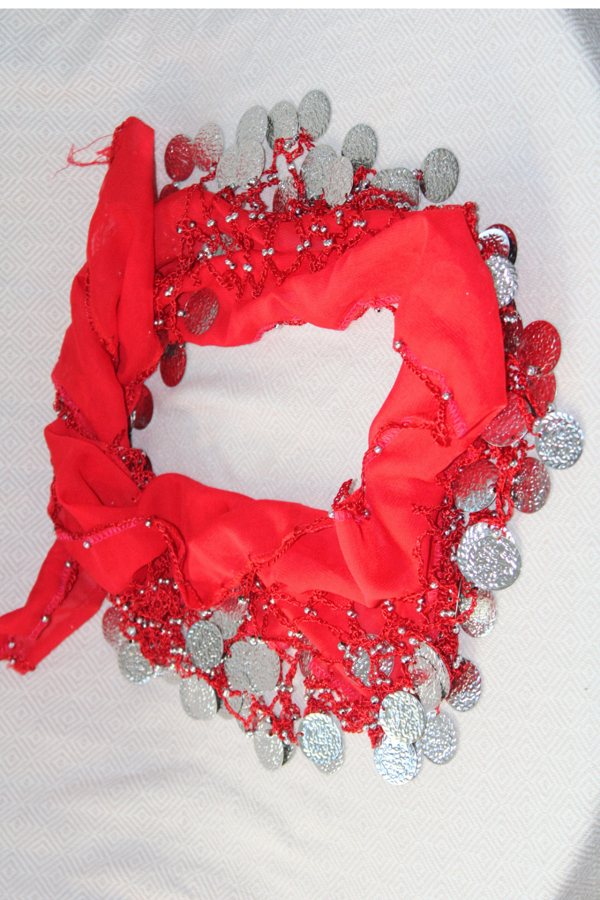 A vibrant red belly dance waist chain featuring two layers of silver coins, draping elegantly around the hips. This shimmering waist scarf adds sparkle and style to your belly dancing performance.